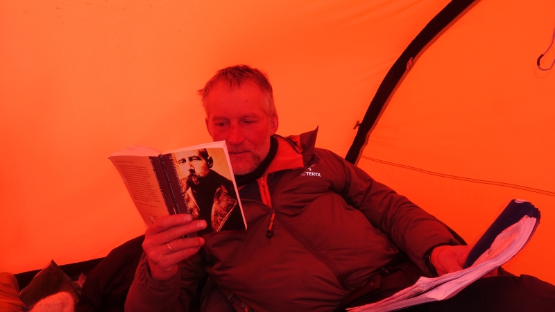 Mann leser bok i telt.