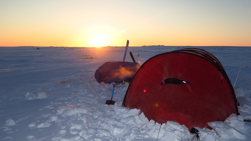 oppslått telt i snøen med sol som går ned